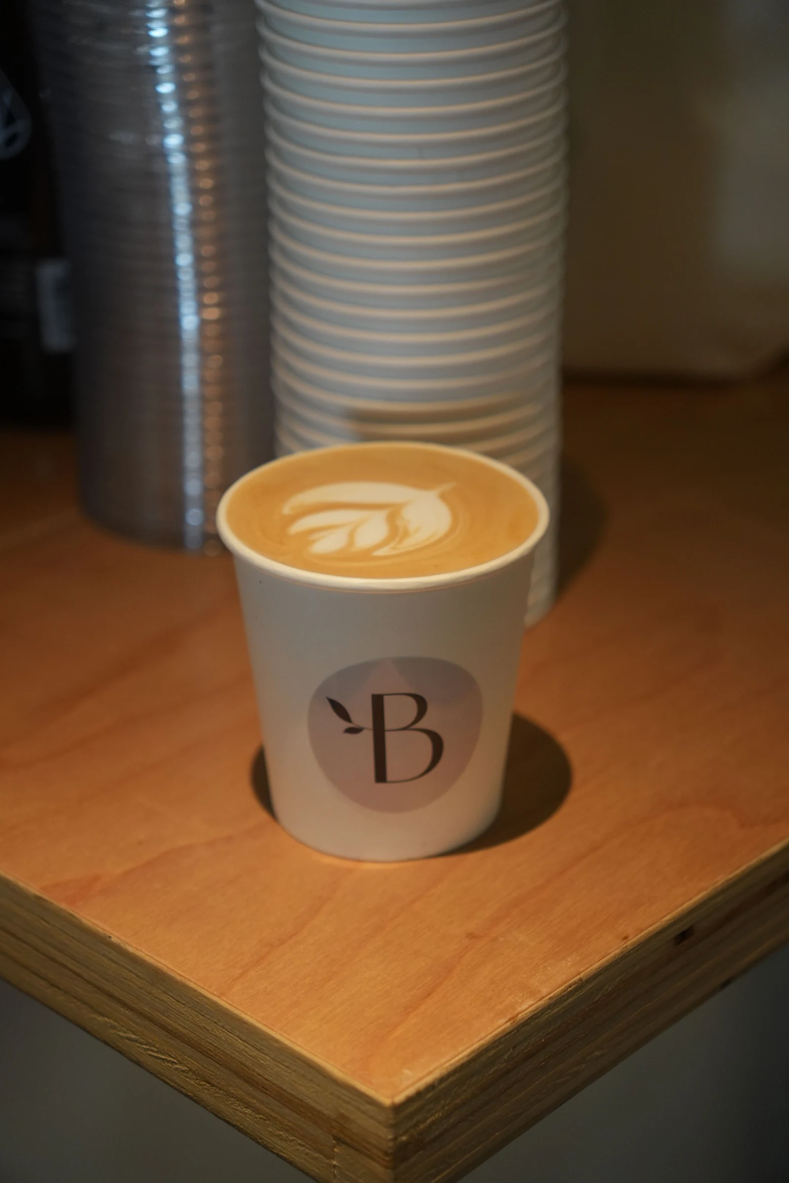 Fresh latte art in a Bloom Coffee cup on the wooden counter